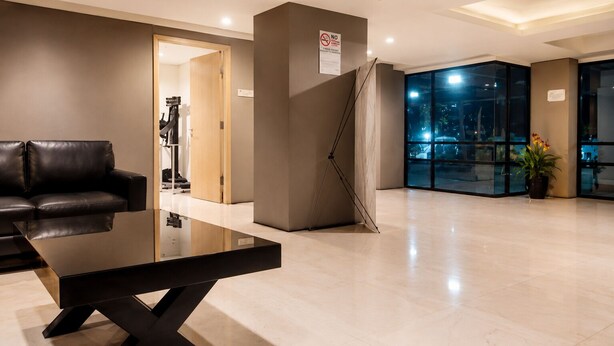 A modern lobby with a glass partition, a black leather sofa, a glass coffee table, and a potted plant. - 19 AVENUE Meeran By Reccoma (Tangerang)