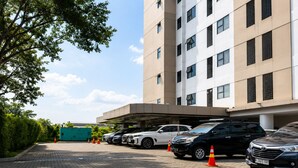 A parking area with multiple cars, a building with a modern design, and a clear sky. - 19 AVENUE Meeran By Reccoma (Tangerang)