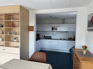 A compact hotel room with a kitchenette, a bed, a wooden wardrobe, and a small seating area. - Holiday home Bohemien in Sint Maartenszee in Callantsoog. Suitable for 6 people with 3 bedrooms. (Sint Maartensvlotbrug)