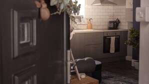 Una cocina moderna con azulejos blancos, una mesa de madera y una puerta oscura.