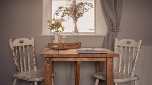Una mesa de comedor con dos sillas, una ventana que da a un paisaje de árboles y un radiador.