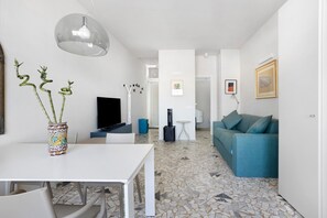 Ein modernes Wohnzimmer mit einem weißen Tisch, einem blauen Sofa, einem Fernseher und einer außergewöhnlichen Bambus-Skulptur.