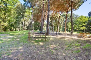 Ein Park mit Trainingsgeräten, Picknicktischen und Bäumen.