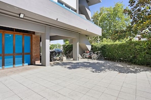 Ein modernes Gebäude mit überdachtem Parkplatz, Fahrrädern und einer Backsteinmauer.