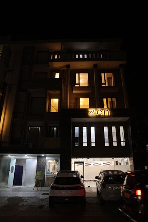 A building with a 'zen' sign, multiple windows, and parked cars in front.