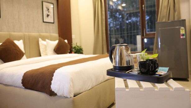 A hotel room with a bed, a tray with a kettle, cups, and a card, and a refrigerator. - Hotel Zen Inn (New Delhi)