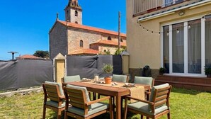 Une terrasse avec une table et des chaises, une petite plante en pot et une vue sur une église dotée d’un clocher.