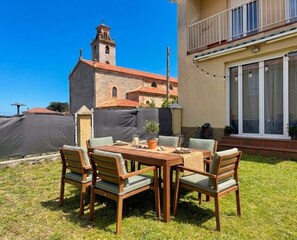 Un patio con una mesa y sillas, una pequeña planta en maceta y vistas a una iglesia con campanario.