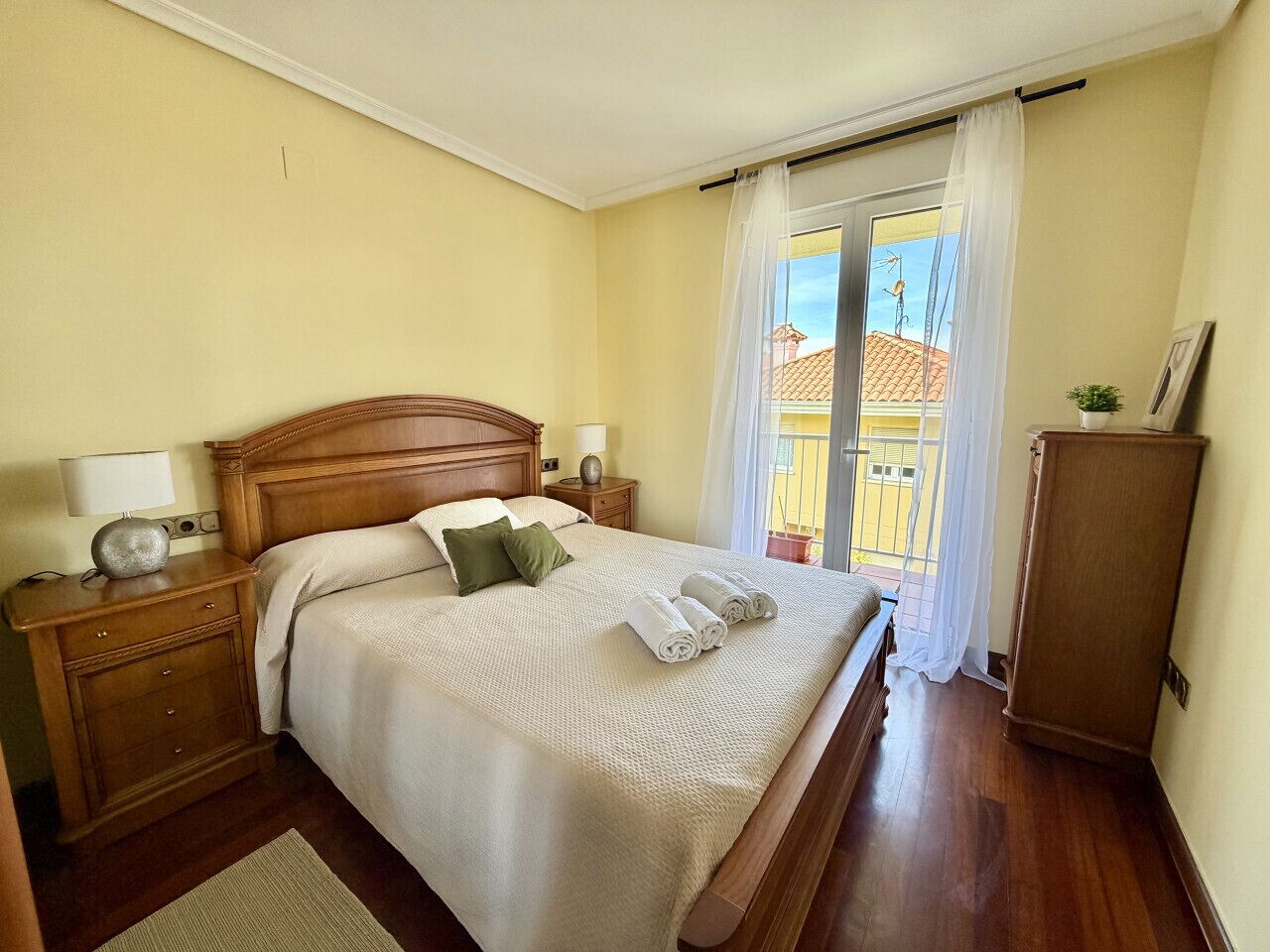 Una cama bien hecha con almohadas, una lámpara de noche y una mesita de noche.