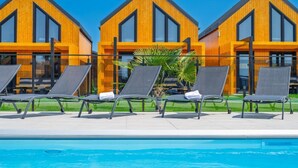 A poolside area with lounge chairs and a clear blue pool. - Holiday Homes With Access to a Pool, Sauna and Jacuzzi (Darlowo)