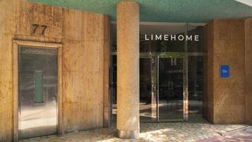 Une entrée d’immeuble avec une porte numérotée, un pilier et une porte vitrée portant l’inscription « LIMEHOME ».