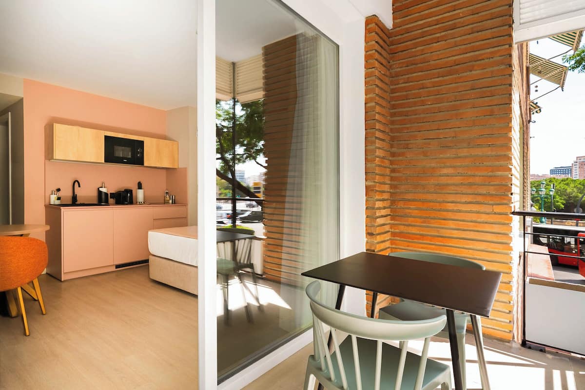 Una cocina moderna con horno empotrado, un comedor con mesa y sillas, y vistas a la ciudad a través de amplios ventanales.