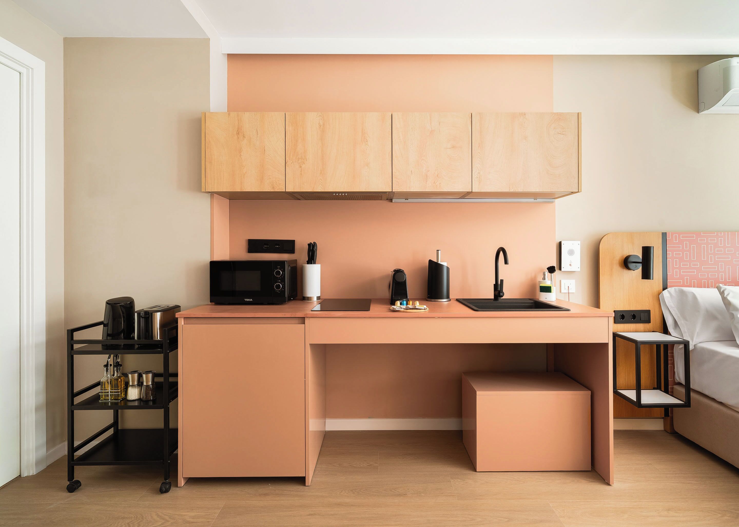 Cocina compacta con microondas, cafetera y lavabo.