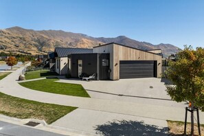 Ein modernes, zweistöckiges Haus mit Garage, überdachter Terrasse und Auffahrt zur Garage.