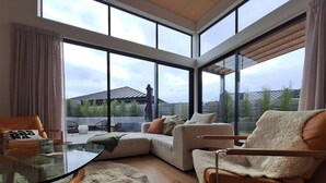 Ett modernt vardagsrum med ett soffbord i glas, en beige soffa och en mjuk matta.