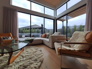 Ein modernes Wohnzimmer mit einem Glastisch, einem beigen Sofa und einem flauschigen Teppich.
