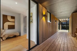Ein modernes Interieur mit Holzboden, einer Bank und einer Glastür zum Außenbereich.