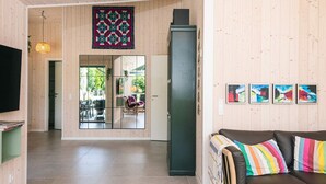 Un interior moderno con piso de madera, un sofá con cojines coloridos, un televisor de pantalla plana y un ventanal grande.