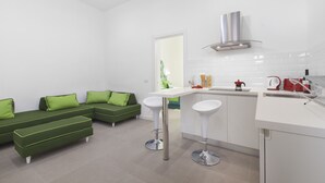 Une cuisine moderne avec un plan de travail blanc, une hotte en acier inoxydable et une bouilloire rouge.