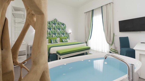 Une chambre d’hôtel avec un lit, une baignoire, une télévision et un objet décoratif en bois.
