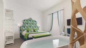 Une chambre à coucher avec un lit, une baignoire blanche, une échelle en bois et une étagère blanche où sont posées des serviettes.