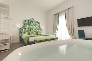 A hotel room with a bed, a bathtub, a TV, and a chair. - Green Suite in Sorrento centre (Sorrento)