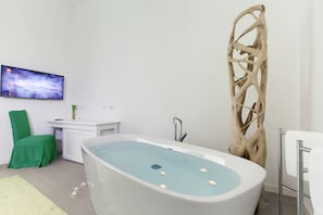 A modern bathroom with a freestanding bathtub, a green chair, a white vanity, and a mounted TV. - Green Suite in Sorrento centre (Sorrento)
