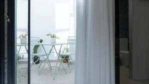 A room with a sliding door leading to an outdoor area with a table and chairs, potted plants, and a view of a bathroom. - Ceramic Rooms Boutique Hostel (Villarreal)