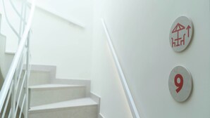 A staircase with white steps and handrails, two wall-mounted signs with a red umbrella symbol and the number 9. - Ceramic Rooms Boutique Hostel (Villarreal)