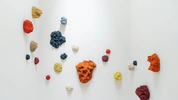 A white wall with scattered colorful clay-like objects.