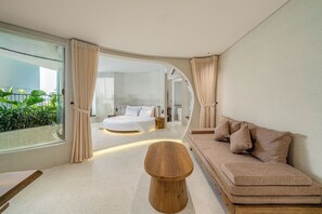 A modern hotel room with a large bed, a sofa, a wooden coffee table, and a view of greenery outside. - Draco Residence Da Nang (Da Nang)
