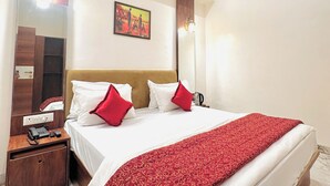 A hotel room with a bed, a nightstand, a ceiling fan, a painting, and a mirror. - Hotel Comfort Zone (Mumbai)
