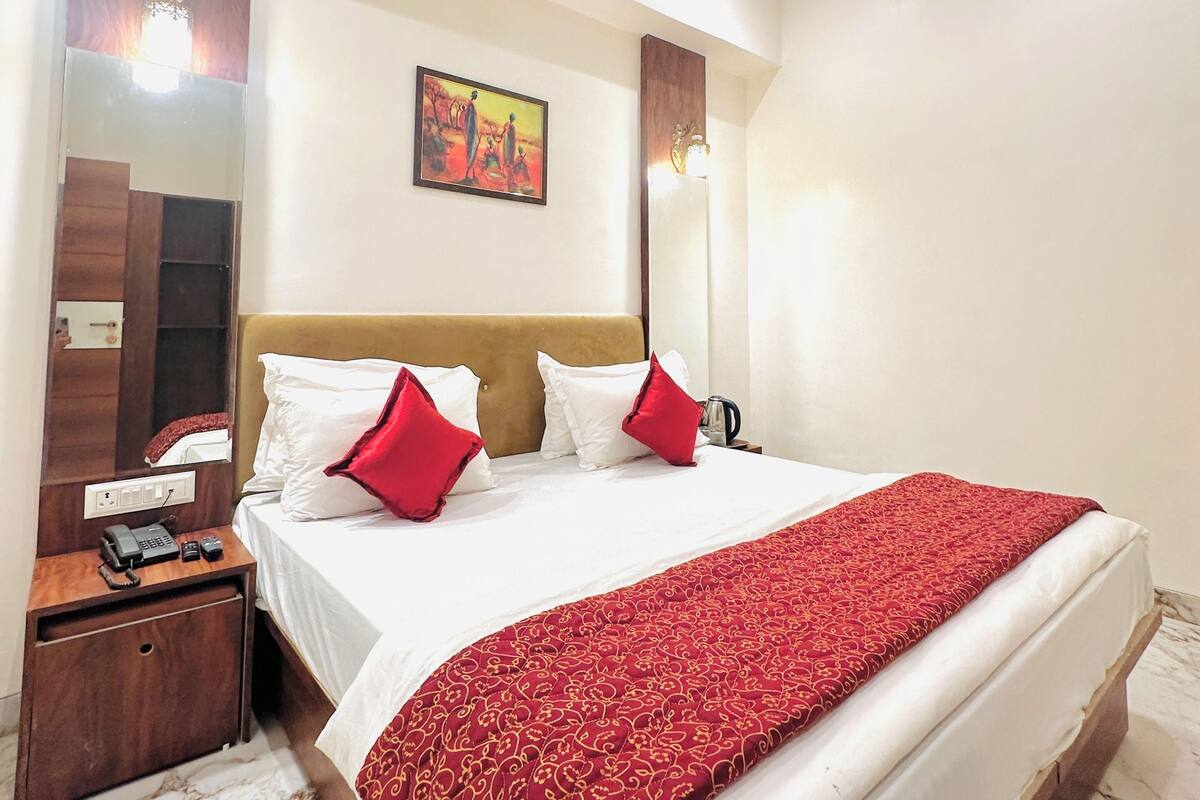 Quarto de hotel com cama, mesa de cabeceira, ventilador de teto, quadro e espelho.