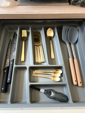 A drawer with compartments containing various utensils and a knife. - Charming cosy Studio in the heart of Aix - Ideal cocoon 🌿 (Aix-les-Bains)
