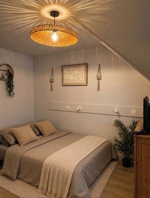 A bedroom with a bed, a hanging light fixture, a wall-mounted shelf, and a potted plant. - Charming cosy Studio in the heart of Aix - Ideal cocoon 🌿 (Aix-les-Bains)