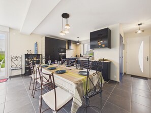A modern kitchen with a dining area, featuring a large island, dark cabinets, and pendant lighting. - 950m from the sea - family home with garden (Piriac-sur-Mer)