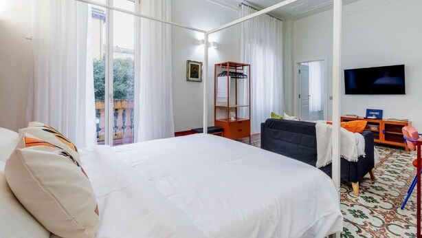 Una habitación de hotel con una cama grande, televisión, escritorio y silla.