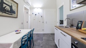 Una cocina compacta con armarios blancos, una encimera de madera, un lavabo y una zona de comedor con una mesa y sillas.
