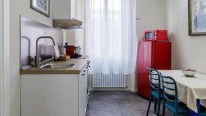 Una cocina compacta con lavamanos, estufa y un refrigerador rojo.