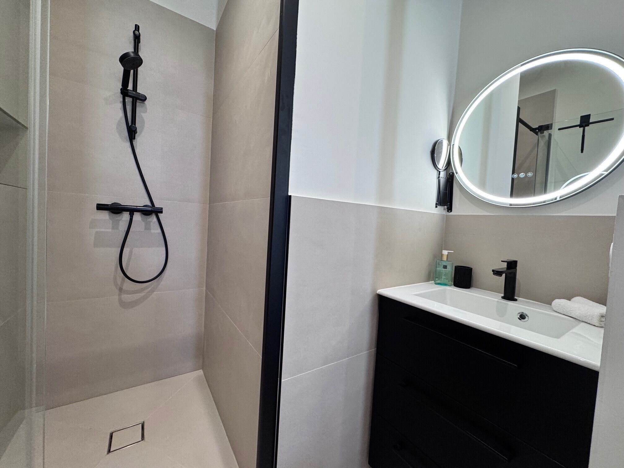 Een moderne badkamer met een douche, wastafel en spiegel.
