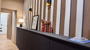 Un comptoir d’accueil avec un mur à rayures, une œuvre d’art encadrée et des objets décoratifs.