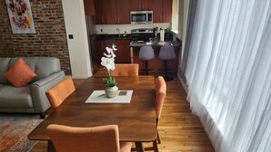 A modern living room with a dining table, sofa, and kitchen in the background. - Apartment in downtown Newark, walking to Penn Sta. (Newark)