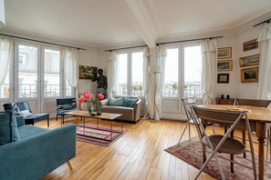Ein Wohnzimmer mit einer Couch, Sesseln, einem Couchtisch und einem Esstisch.