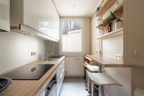 Eine kleine Küche mit eingebautem Herd, Spüle und einem Fenster für natürliches Licht.
