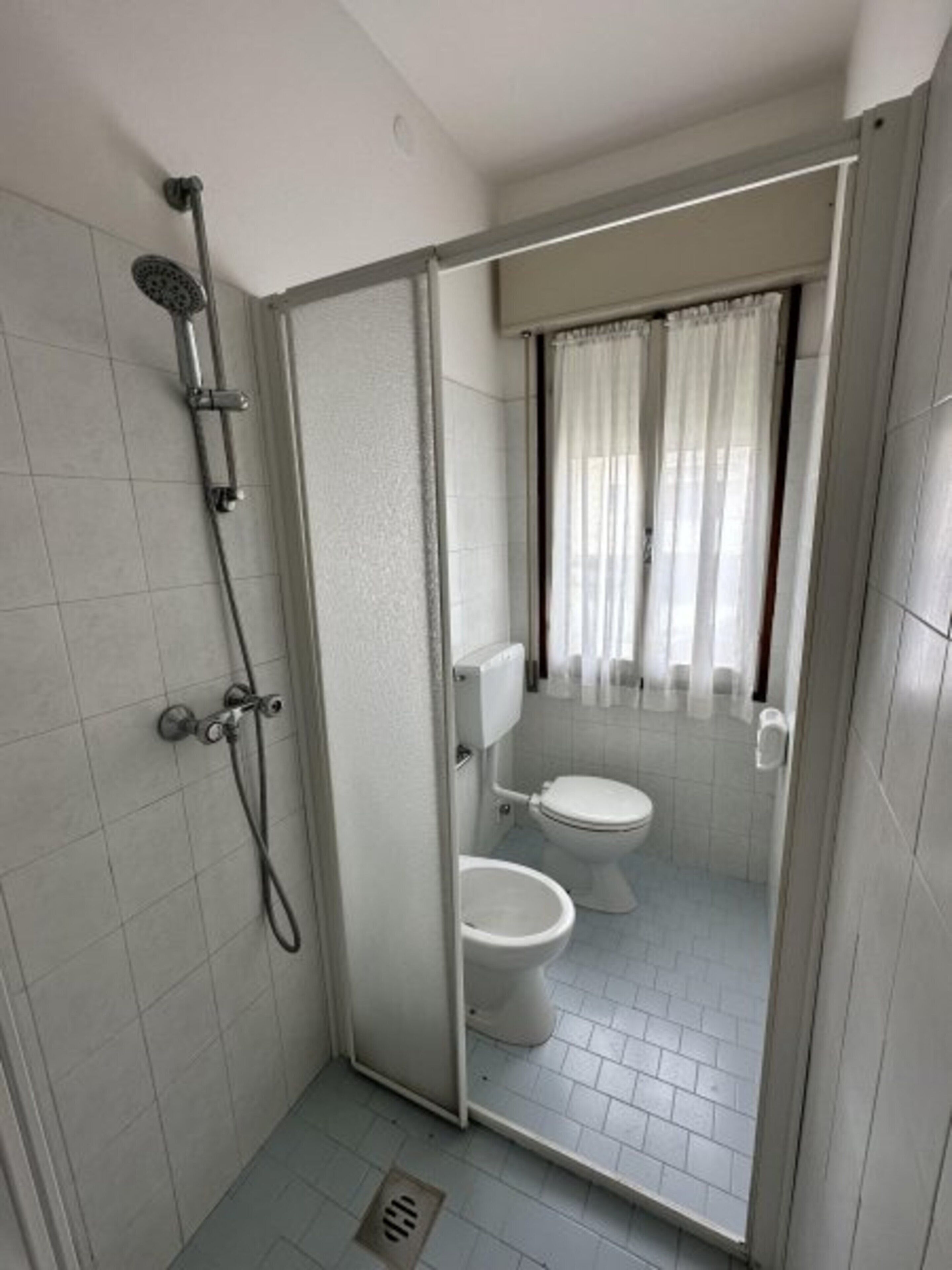 A small, enclosed bathroom with a shower, toilet, and a glass partition.