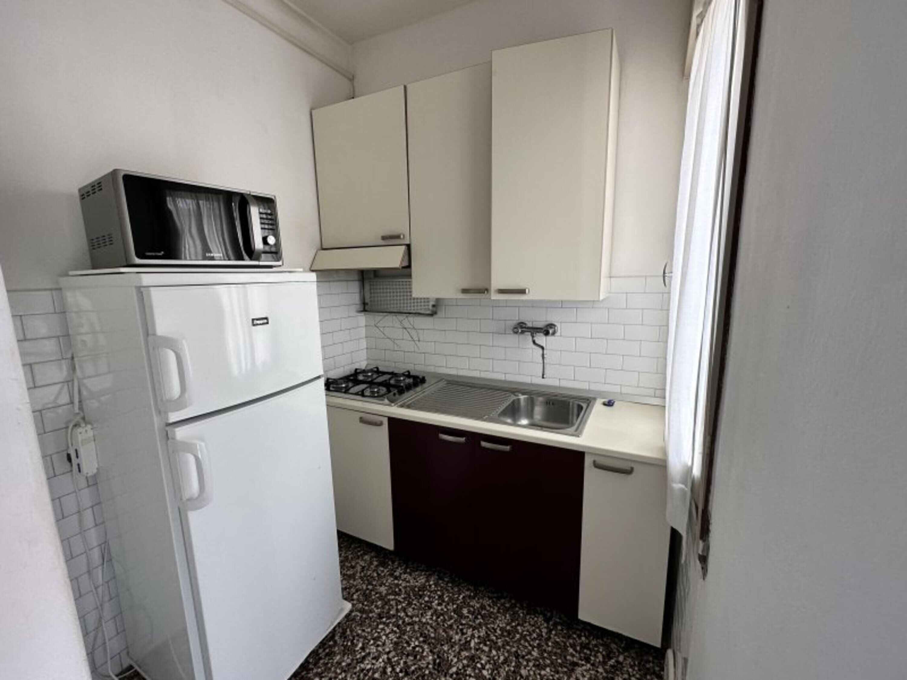 A compact kitchen with white cabinets, a microwave, a stove, and a sink.
