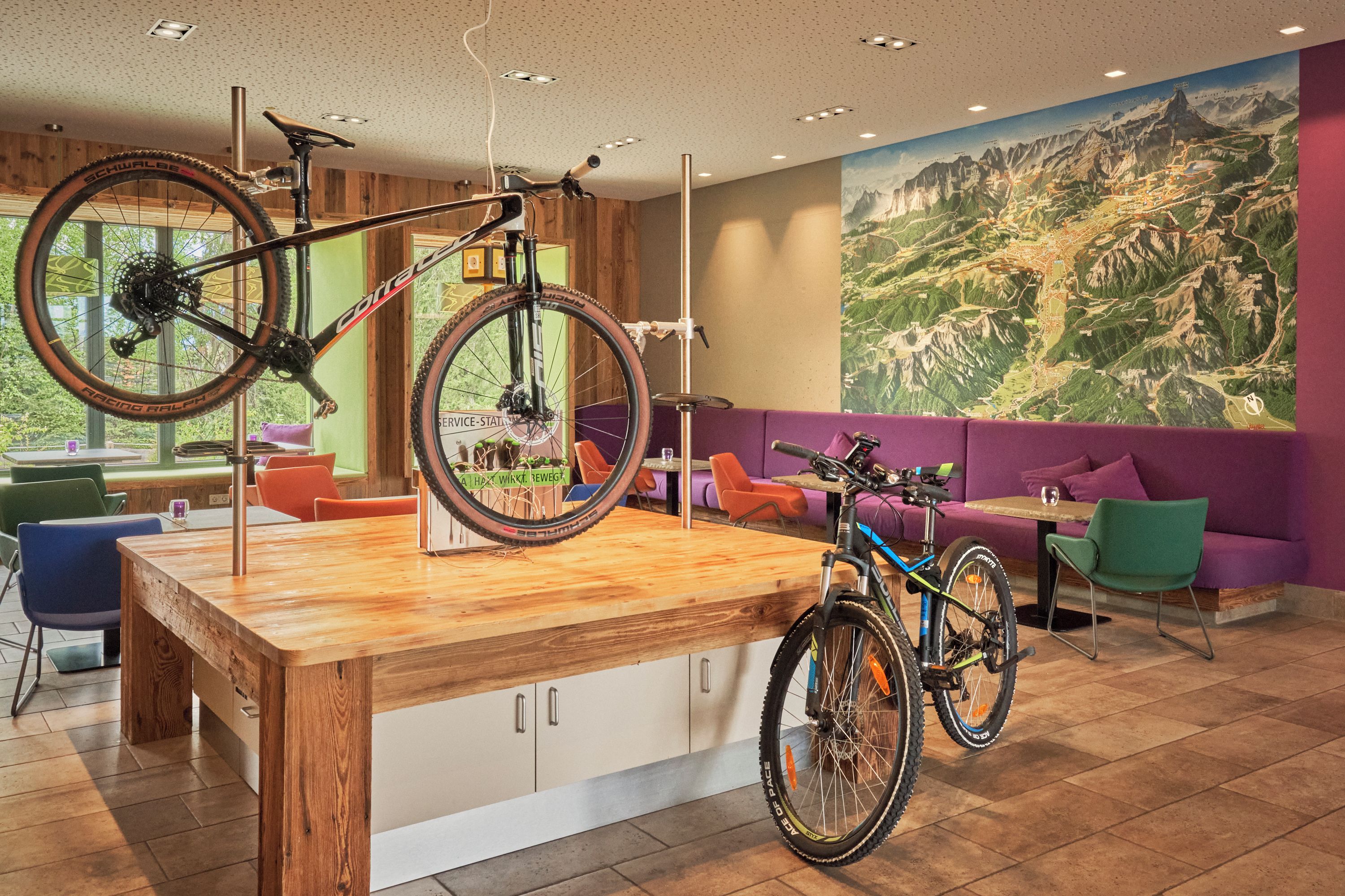 A modern interior with a wooden bar area, seating, and a large mountain landscape mural.