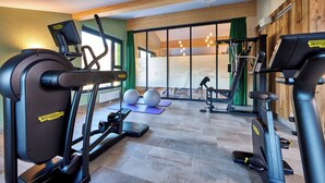 A gym with cardio machines, free weights, and exercise balls.