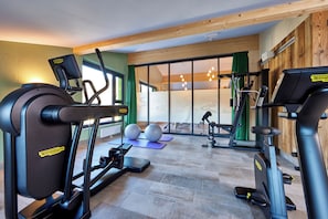 Un gimnasio con máquinas de cardio, pesas libres y pelotas de ejercicio.