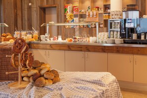A breakfast buffet with various food items and a coffee machine. - Explorer Hotel Bayrischzell (Bayrischzell)